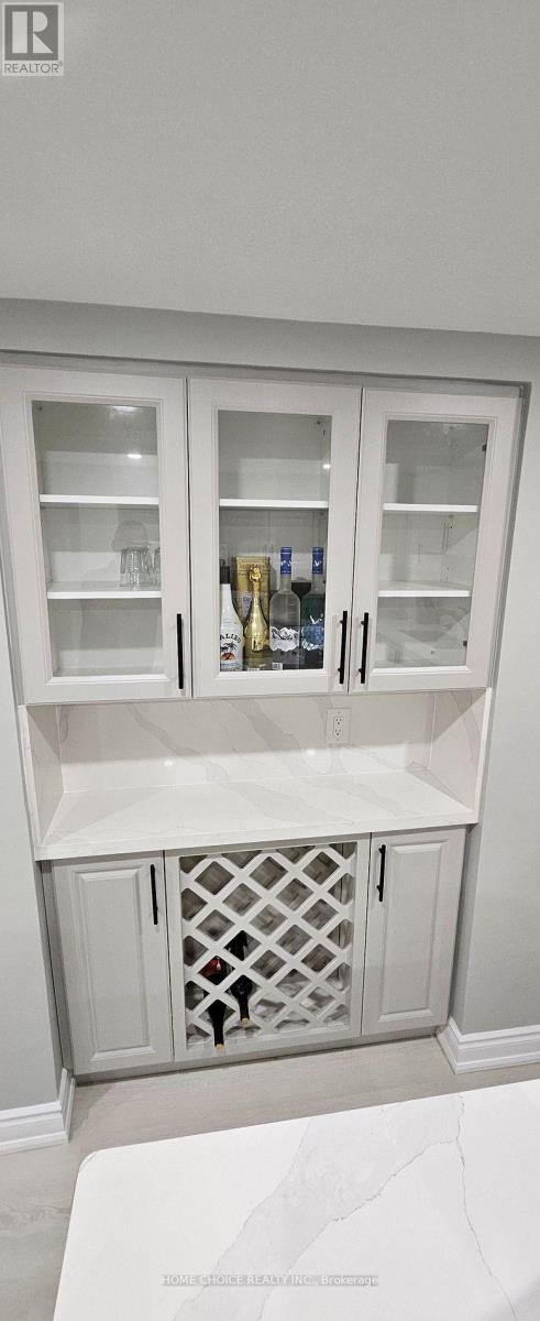 A white cabinet with glass doors and a wine bottle inside.