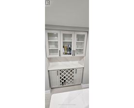 A white cabinet with glass doors and a wine bottle inside.