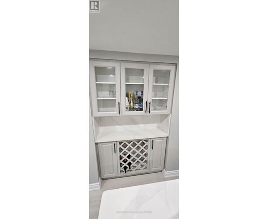 A white cabinet with glass doors and a wine bottle inside.
