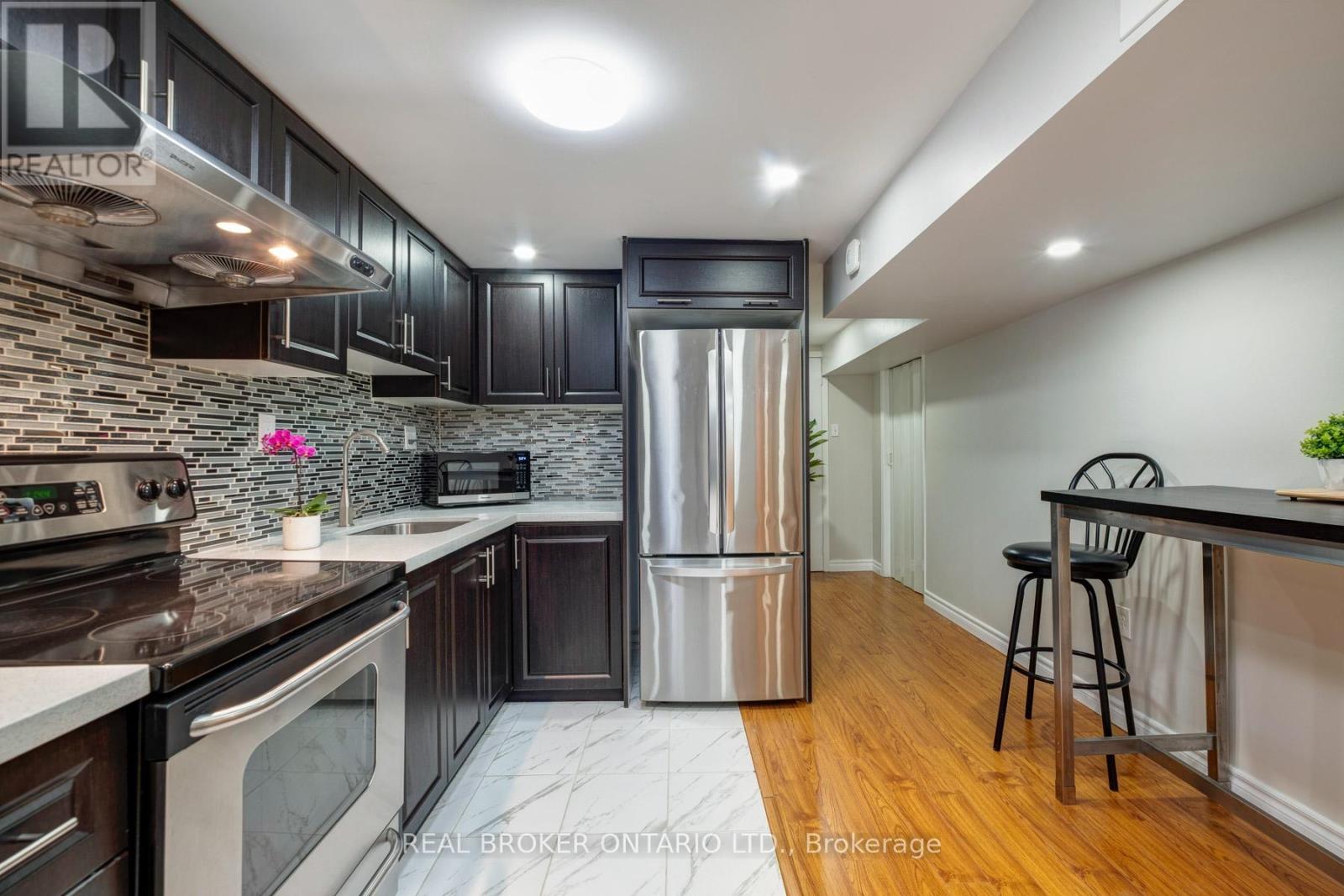 A modern kitchen with dark wood cabinets and stainless steel appliances.