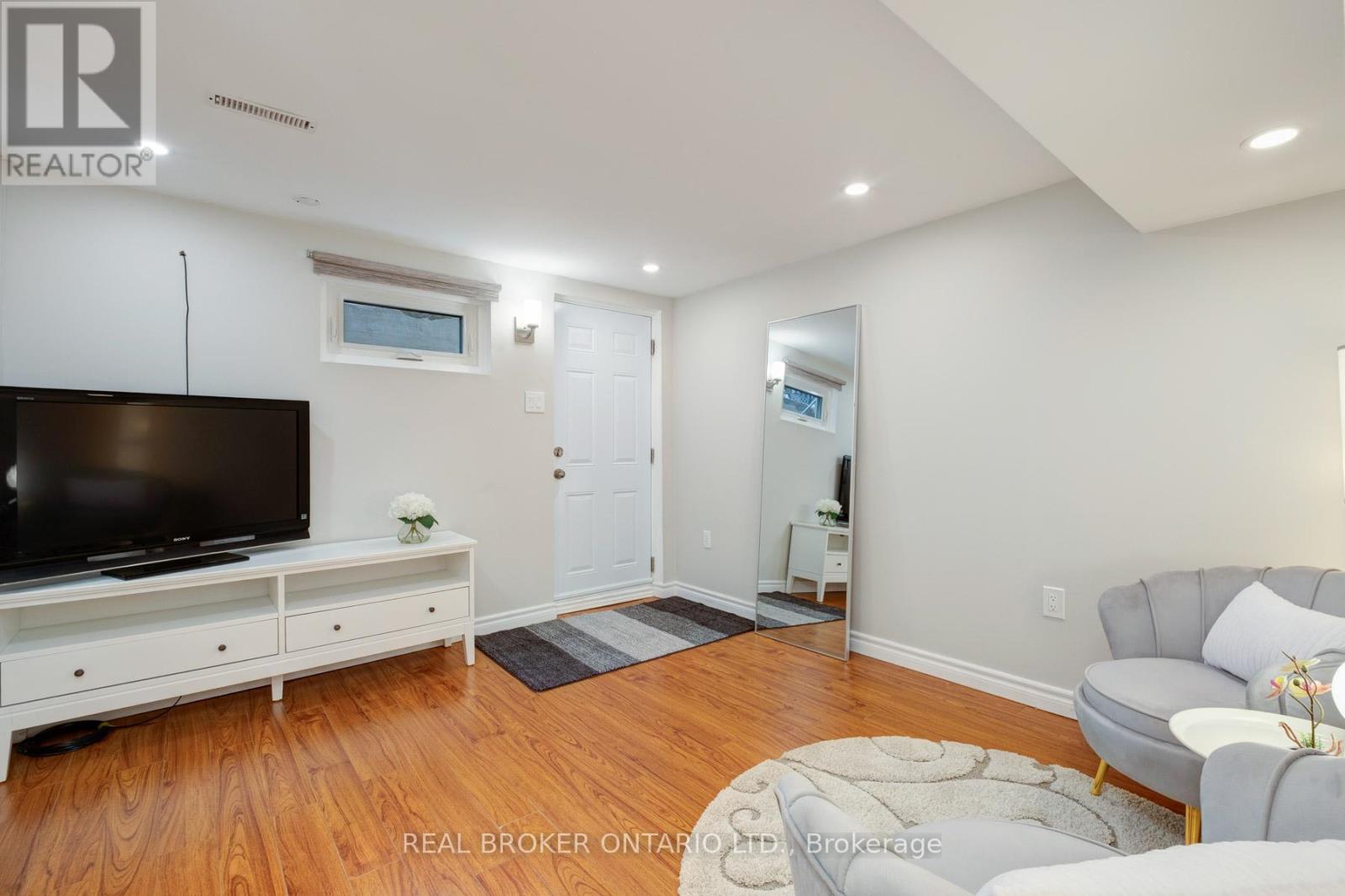 A living room with a flat screen TV and a grey sofa.