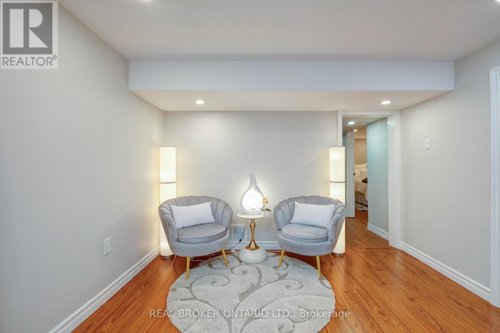 A spacious room with two grey armchairs and a patterned rug.