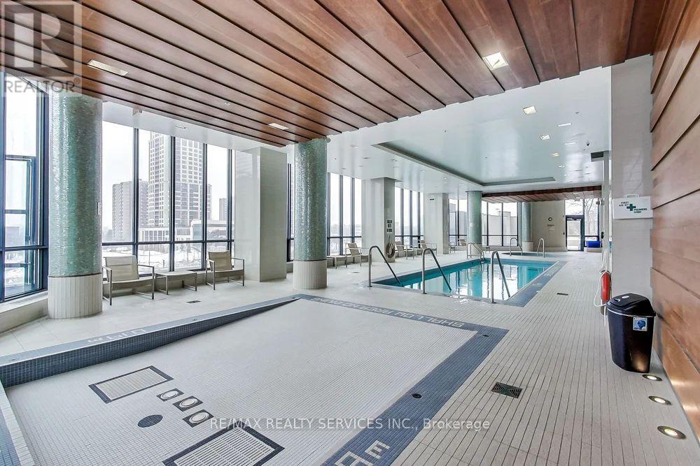 A large indoor swimming pool with a wooden ceiling and a view of the city outside the windows.