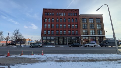 A red brick building with a parking lot in front of it.