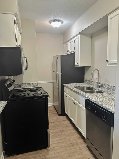 A kitchen with black appliances and white cabinets.