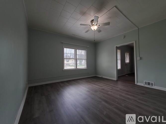 A spacious room with a ceiling fan and wooden flooring.