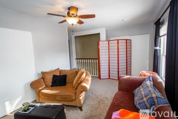 A living room with a brown couch, a brown chair, and a ceiling fan.
