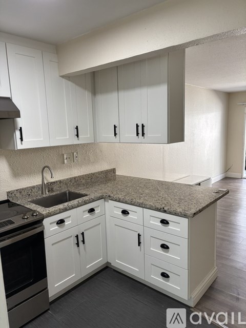 A kitchen with white cabinets and a granite countertop.