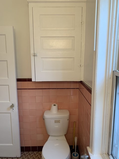 A white toilet in a bathroom with pink tiles.