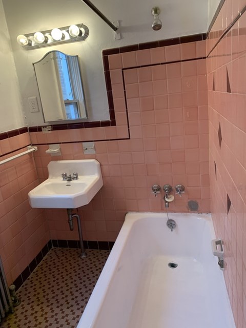 A bathroom with a sink, mirror, and bathtub.