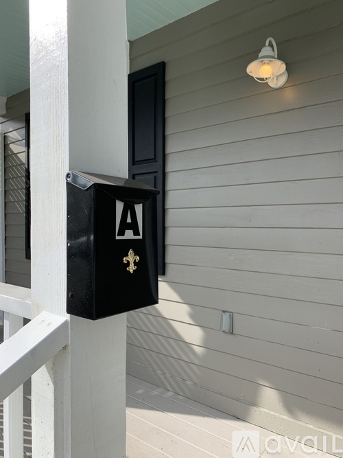 A black mailbox with a gold fleur de lis design on it.