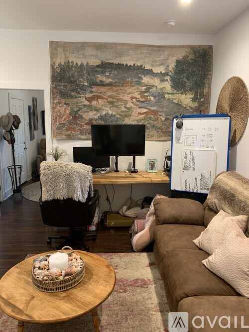 A living room with a large painting on the wall and a couch with a pillow on it.