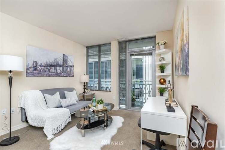 A living room with a grey couch, a coffee table, a white chair, and a painting on the wall.