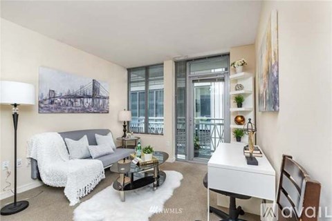 A living room with a grey couch, a coffee table, a white chair, and a painting on the wall.