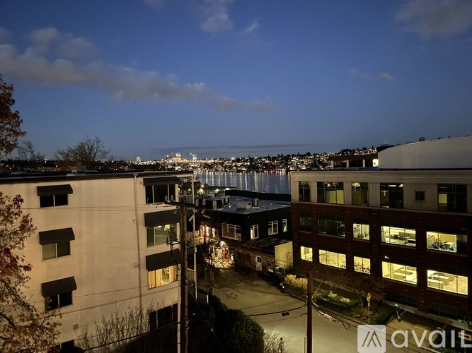 A cityscape at dusk with buildings and a bridge in the distance.