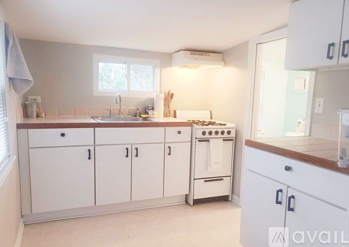 A kitchen with white cabinets and a stove top oven.