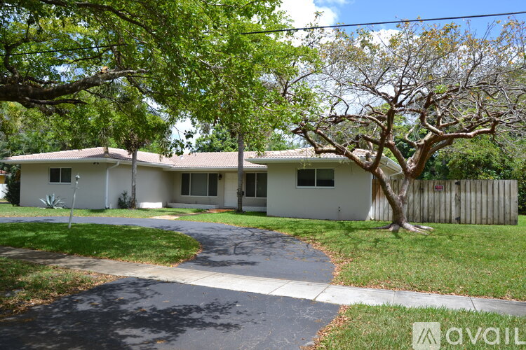 A house with a driveway and a tree in front of it.