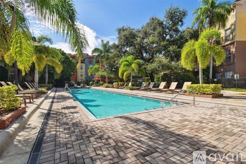 A swimming pool surrounded by palm trees and lounge chairs.