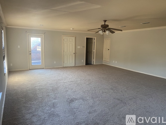 A spacious room with a carpeted floor and a ceiling fan.