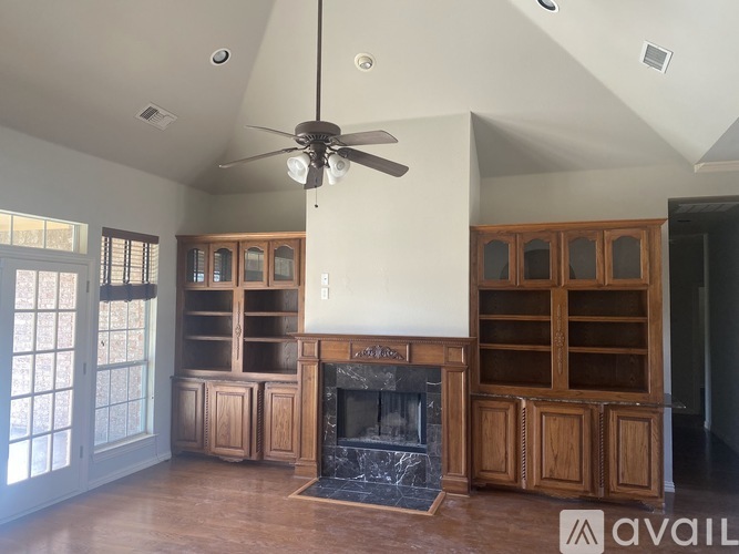 A living room with a fireplace and a ceiling fan.