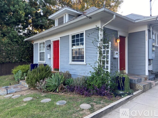 A blue house with red doors and windows is for sale.