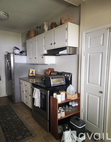A kitchen with white cabinets and a black counter top.