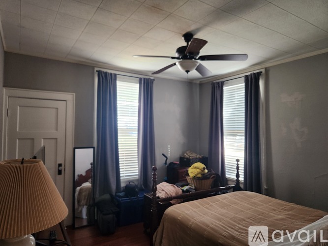 A bedroom with a bed, a dresser, a mirror, a ceiling fan, and a lamp.