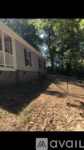 A house with a fence and trees in the background.