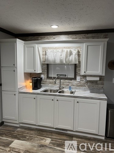 A kitchen with white cabinets and a stone backsplash.