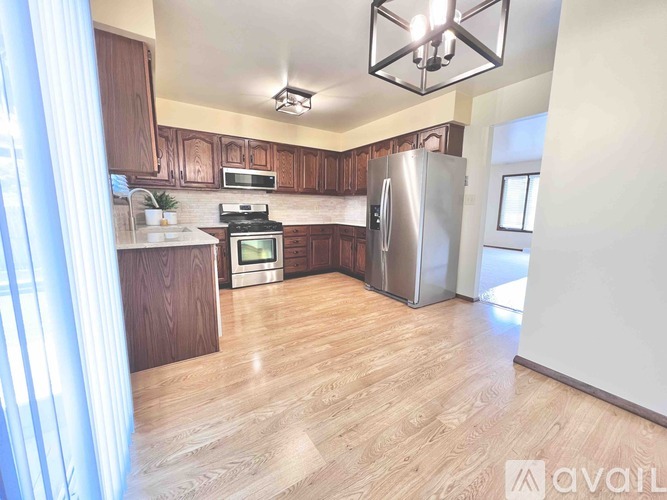 A kitchen with wooden cabinets and a stainless steel refrigerator.