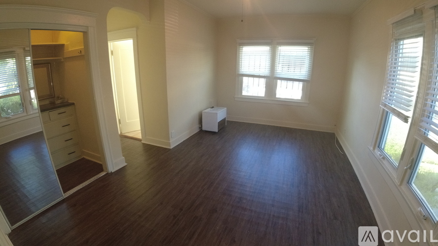 A room with wooden flooring and a white refrigerator.