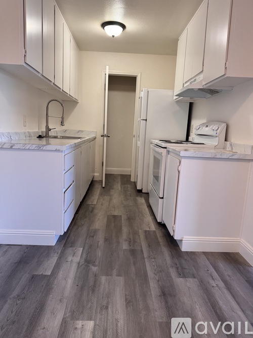 A kitchen with white cabinets and a marble countertop.