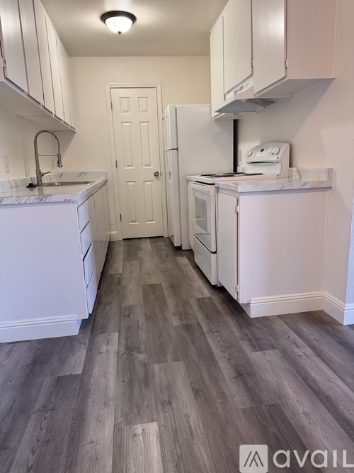A kitchen with white cabinets and a grey floor.