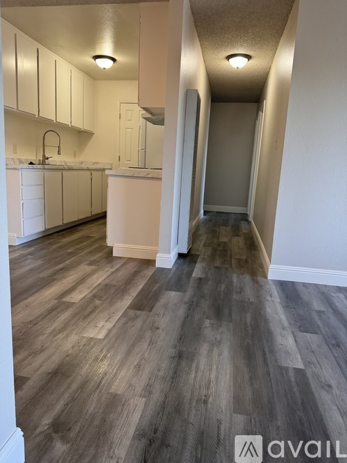 A kitchen with white cabinets and a wooden floor.