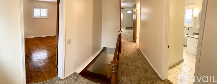 A hallway with a carpeted floor and white walls.