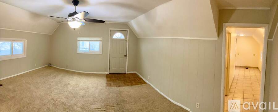 A spacious room with a ceiling fan and two windows.