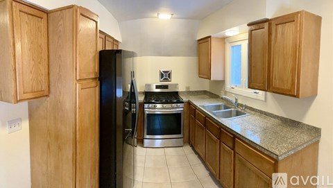 A kitchen with wooden cabinets and a black refrigerator.