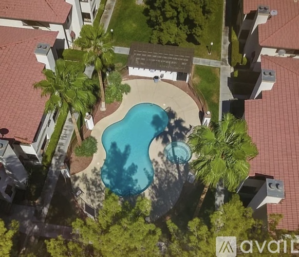 An aerial view of a swimming pool surrounded by palm trees and buildings.
