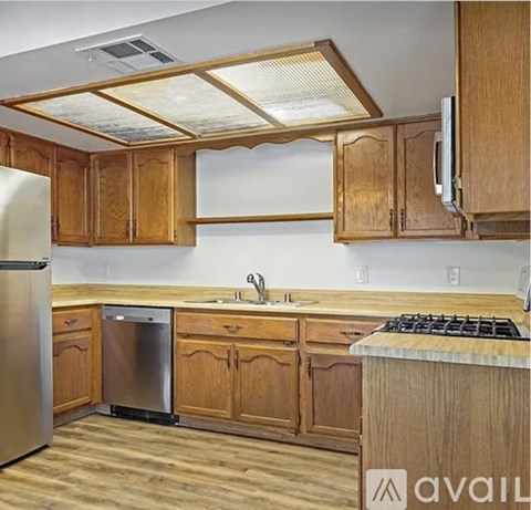 A kitchen with wooden cabinets and a stainless steel dishwasher.