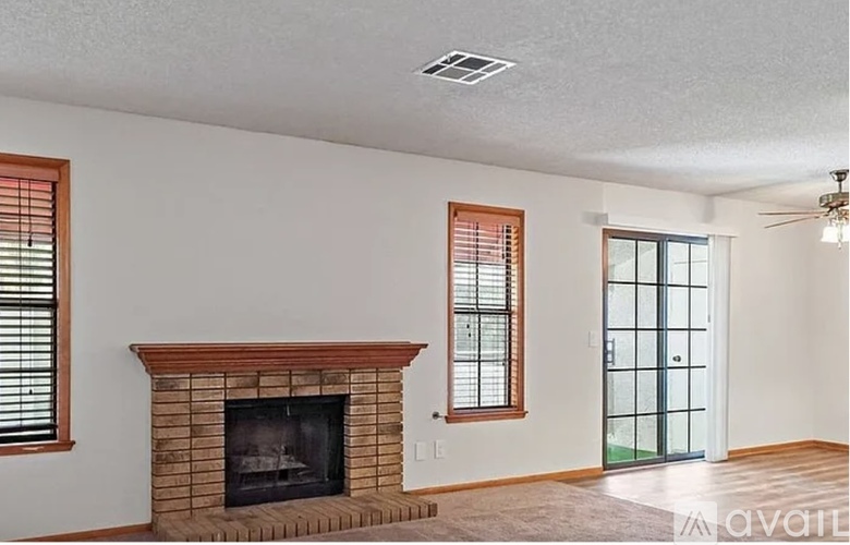 A living room with a fireplace and a door leading to a balcony.