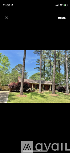 A house with a green lawn and trees in front.