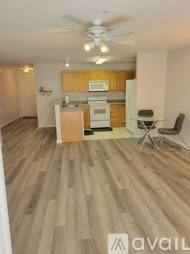 A kitchen with wooden floors and a ceiling fan.