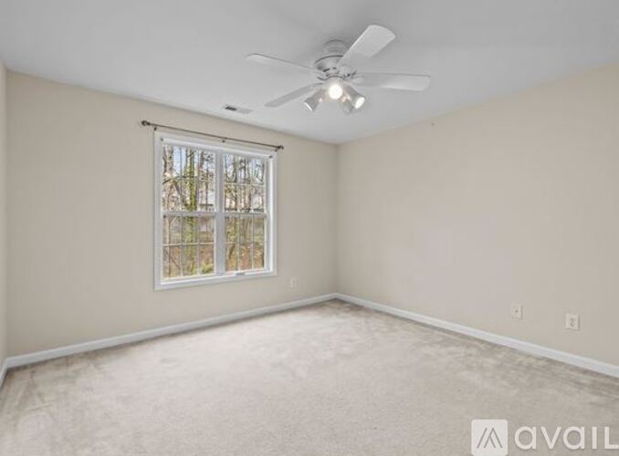A room with a ceiling fan and a window with blinds.