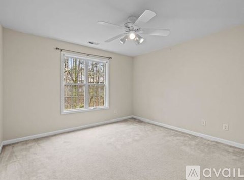 A room with a ceiling fan and a window with blinds.