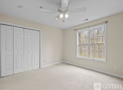 A room with a ceiling fan and a window with blinds.