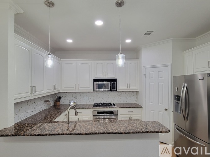 A kitchen with white cabinets and a granite countertop.
