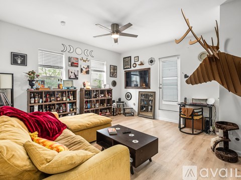 A living room with a yellow couch and a deer head mounted on the wall.