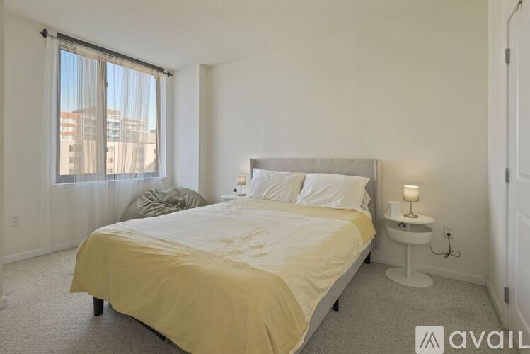 A bedroom with a large bed and a window with curtains.