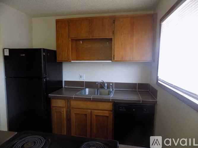 A kitchen with wooden cabinets and a black refrigerator.