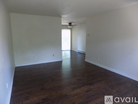 A spacious room with wooden floors and white walls.